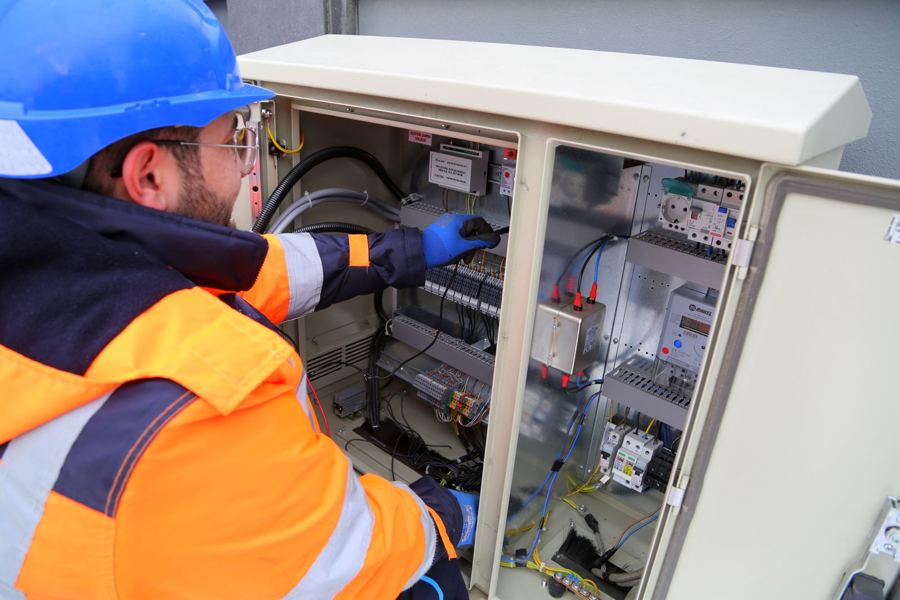 Electrician in safety gear inspecting an outdoor panel